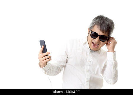 L'Asian senior homme à écouter la musique sur le fond blanc. Banque D'Images