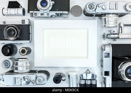 Cadre photo vide avec de vieux appareils photo classiques, d'équipements et d'accessoires en bois blanc sur l' affichage d'arrière-plan Banque D'Images
