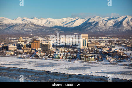 Vue aérienne de la neige couvrant le centre-ville d'Anchorage et les montagnes de Chugach au loin, Cook Inlet en premier plan, centre-sud de l'Alaska en wi... Banque D'Images