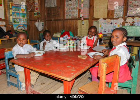 Les enfants de l'école préparatoire Nanyuki quatre assis autour de la table tout en ayant leur déjeuner, le Kenya. Banque D'Images