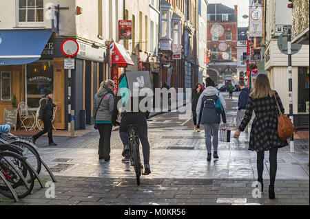 Deliveroo employé sur un push bike la prestation de fast food avec une zone de livraison sur son dos dans la ville de Cork, Irlande Banque D'Images