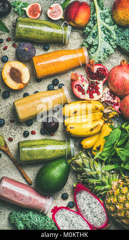 Télévision à jeter des smoothies colorés dans des bouteilles avec des fruits tropicaux frais et légumes sur fond de béton, vue du dessus, la composition verticale. En bonne santé, ve Banque D'Images