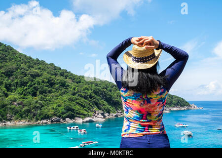 Traveller femme avec maillot coloré les bras levés au ciel en haut de montagne avec vue sur l'océan bleu et la vitesse bateau en mer vacances d'été,voyager Banque D'Images