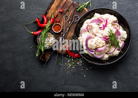 Brochettes marinées au barbecue pour l'oignon, le piment et les épices. Pour la viande de porc cru épicé shish kebab en brochettes sur fond noir, vue du dessus Banque D'Images