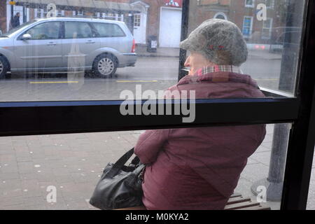 Une femme se trouve au pensionné d'un arrêt de bus en attendant le bus à Brentwood Essex UK Banque D'Images