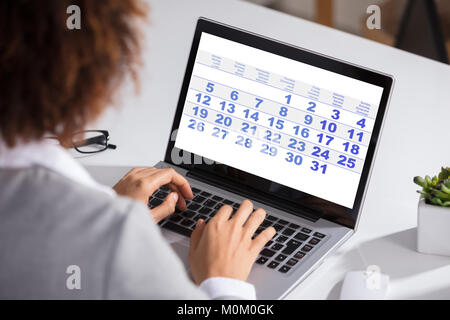 Close-up of a Woman du Calendrier avec l'ordre du jour quotidien On laptop computer Banque D'Images