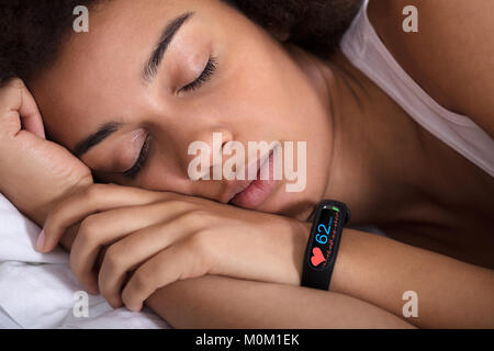 Close-up of Smartwatch montrant le taux de pulsation sur Sleeping Woman's Hand Banque D'Images