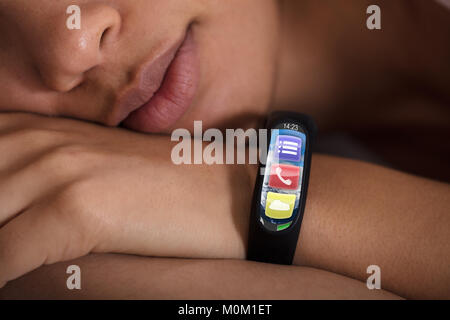 Close-up of Smartwatch montrant le taux de pulsation sur Sleeping Woman's Hand Banque D'Images