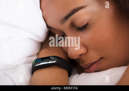 Close-up of Woman Sleeping On Bed With Smartwatch montrant le taux de pulsation Banque D'Images