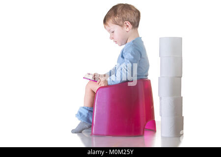 Baby sitting sur pot de chambre en lisant un livre. Concept de formation de pot Banque D'Images