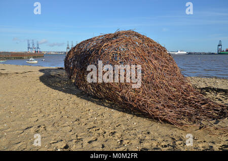 Une sculpture sur la plage à Harwich, Essex, avec le port de Felixstowe dans la distance entre le port de Harwich Banque D'Images