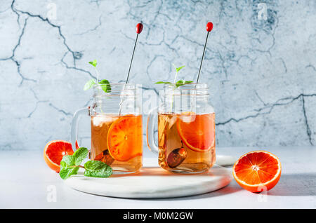 Thé glacé traditionnel avec orange et menthe et de la glace dans des pots Mason . jolie boisson d'été sur conseil en marbre blanc Banque D'Images