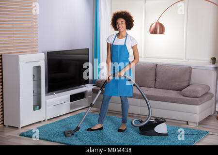 Jeune femme avec Tapis Nettoyage Nettoyeur aspirateur dans la salle de séjour Banque D'Images