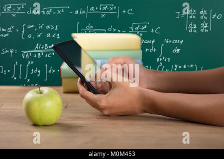 Close-up of a student's Hand Using Digital Tablet avec livres empilés sur 24 Banque D'Images