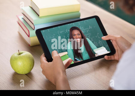 La main de l'élève la visioconférence avec Enseignante On Digital Tablet Banque D'Images