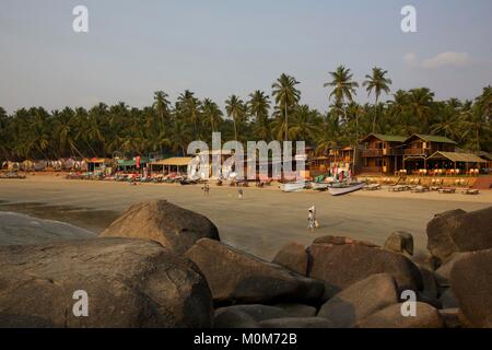 L'Inde, Goa Palolem,touristes,marcher dans la plage de sable doré bordée de restaurants et boutiques, entre les rochers et arbres cocnut Banque D'Images