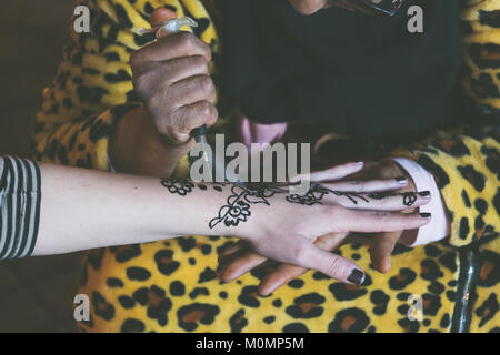 Femme musulmane est en train de faire un tatouage au henné temporaire sur une main de fille blanche Banque D'Images