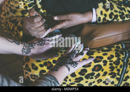 Femme musulmane est en train de faire un tatouage au henné temporaire sur une main de fille blanche Banque D'Images