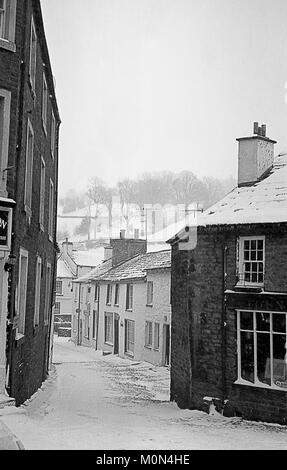 Main Street, Dent, en hiver la neige, Cumbria, England, UK. Old b/w film photo. Banque D'Images