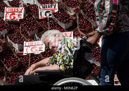 Femme handicapée dans un fauteuil roulant à roues étant passé d'une cerise au Marlyebone Street Food Festival lors d'une journée ensoleillée à Londres Angleterre Royaume-uni Banque D'Images