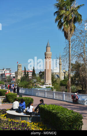 Antalya, Turquie - 26 mars 2014 : Les gens se reposant dans le parc contre minaret Yivli. Construit en XIV siècle, ce minaret de 38 mètres de haut est maintenant le symbo Banque D'Images