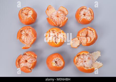 L'orange pelée et la moitié-mandarines pelées sont distribués sur un carré sur un fond gris. Banque D'Images