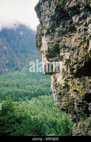 Deux hommes d'une escalade falaise en surplomb de l'embranchement nord de la rivière Snoqualmie, Washington, USA. Banque D'Images