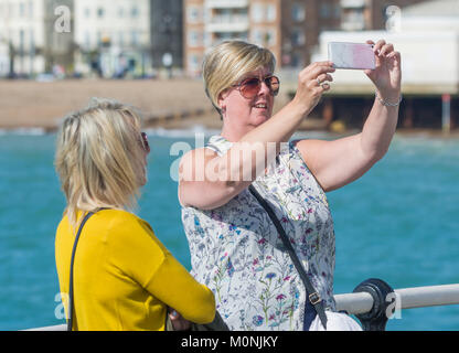 Un couple d'amies à la mer en tenant vos autoportraits sur un smartphone au Royaume-Uni. Banque D'Images