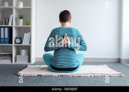 Pregnant woman practicing yoga exercice à la maison. Le yoga et la grossesse à l'intérieur concept de remise en forme. Images à faible contraste hors cadre naturel avec la lumière de la fenêtre. Banque D'Images