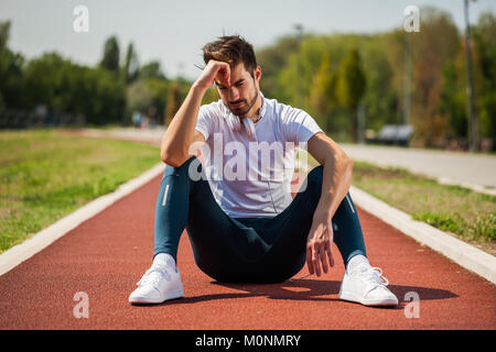Jeune homme s'est blessé en faisant du jogging sur la journée ensoleillée. Banque D'Images