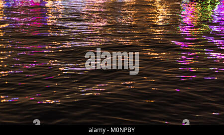 Neon light réflexes couleur sur l'eau produisent une grande variété de nuances de couleur rougeoyante. Banque D'Images