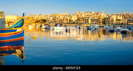 Les pêcheurs et les bateaux de passagers à Marsaskala bay dans le sud de Malte au début de la soirée Banque D'Images