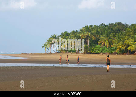 Costa Rica, Osa peninsula,Femmes marchant sur une plage de sable brun bordé de cocotiers Banque D'Images