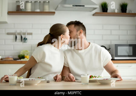 Loving couple enjoying meal embrassant assis à ta cuisine salle à manger Banque D'Images