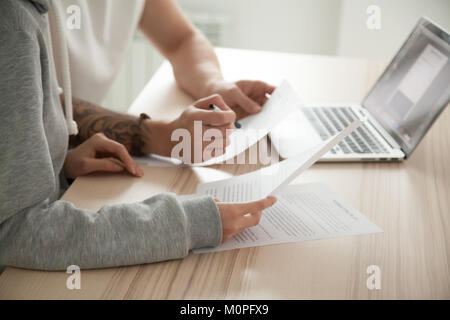 Couple holding la lecture de documents à la maison avec un ordinateur portable, Close up Banque D'Images