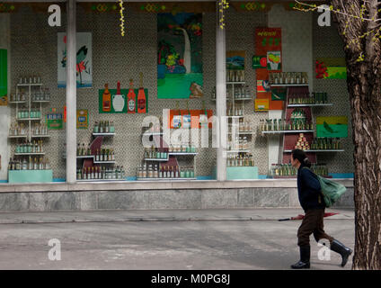 Femme de la Corée du Nord en passant en face d'un magasin de boissons, de la province de Pyongan, Pyongyang, Corée du Nord Banque D'Images