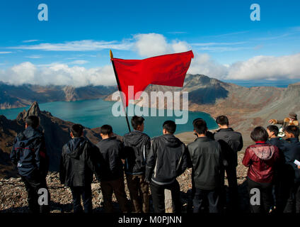 Groupe d'étudiants avec drapeau rouge en face du lac au mont mont Paektu, Ryanggang Province, Mont mont Paektu, la Corée du Nord Banque D'Images