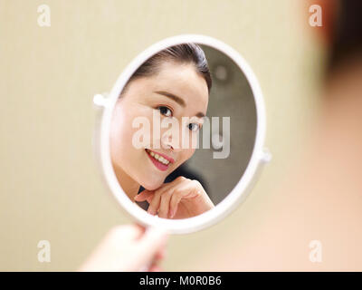 Belle jeune femme asiatique se voir en miroir, heureux et souriant. Banque D'Images