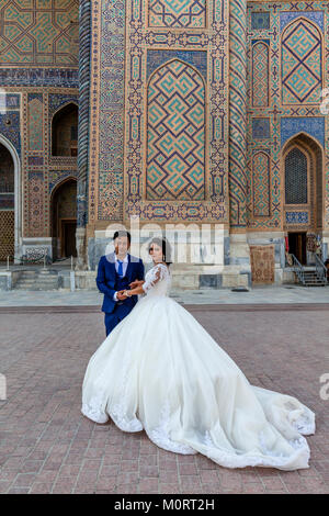 Un 'juste' jeune couple mariés posent pour une photo au complexe du Registan, Samarkand, Ouzbékistan Banque D'Images