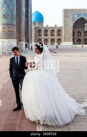 Un 'juste' jeune couple mariés posent pour des photos au complexe du Registan, Samarkand, Ouzbékistan Banque D'Images