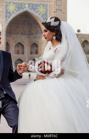 Un 'juste' jeune couple mariés posent pour des photos au complexe du Registan, Samarkand, Ouzbékistan Banque D'Images