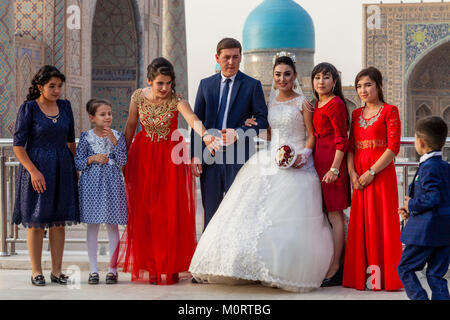 Un 'juste' jeune couple mariés posent pour des photos de mariage au complexe du Registan, Samarkand, Ouzbékistan Banque D'Images