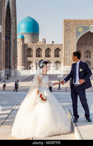 Un 'juste' jeune couple mariés posent pour des photos de mariage au complexe du Registan, Samarkand, Ouzbékistan Banque D'Images