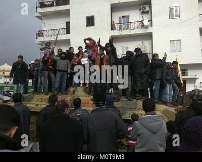 La photographie capture un moment de la guerre civile libyenne de 2011, en particulier la célébration à Al Bayda le 25 février 2011, marquant une victoire significative pour les forces anti-Kadhafi. L'image dépeint l'atmosphère de jubilation alors que les citoyens et les rebelles se réjouissent dans les rues, agitant des drapeaux et exprimant leur nouvel espoir au milieu du conflit. Banque D'Images