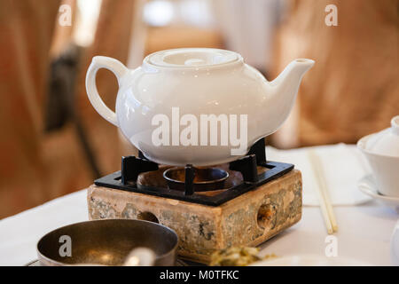 Pot de thé chinois sur brûleur pour plateau de brassage au cours de dim sum traditionnels repas. Banque D'Images