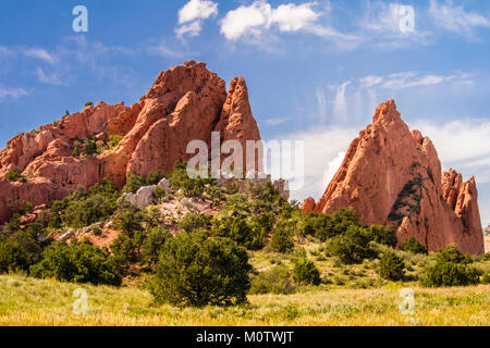 Vue de l'étonnant Jardin des Dieux Park à Colorado Spring, Colorado ; l'herbe verte, les arbres et arbustes en premier plan ; des formations de roche lunatique Banque D'Images