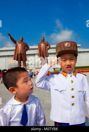 Garçon nord-coréen habillé en soldat devant les deux statues de la Chers Leaders dans le grand monument sur la colline Mansu, province de Pyongan, Pyongyang, Corée du Nord Banque D'Images