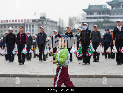 Garçon en passant en face de jeunes femmes de la Corée du Nord lors d'une répétition des jeux de masse à la place Kim Il Sung, de la province de Pyongan, Pyongyang, Corée du Nord Banque D'Images