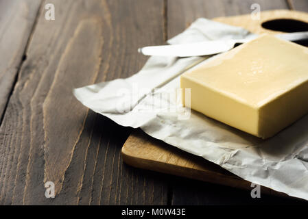 Le beurre frais de la ferme de Pat sur une planche en bois et l'aluminium avec un couteau Banque D'Images