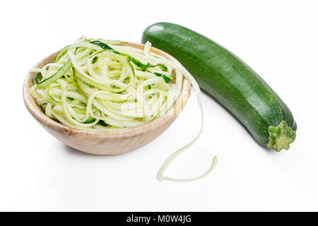 Courgette cru nouilles dans une cuvette en bois rustique isolated on white Banque D'Images